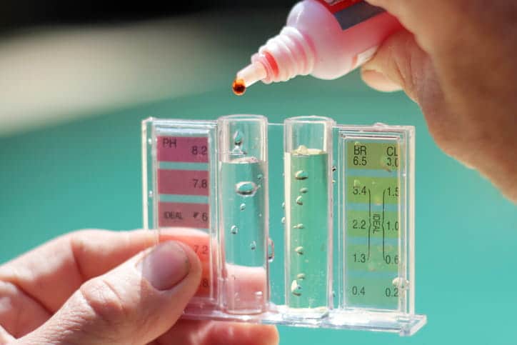 A person testing their water quality with drops. 