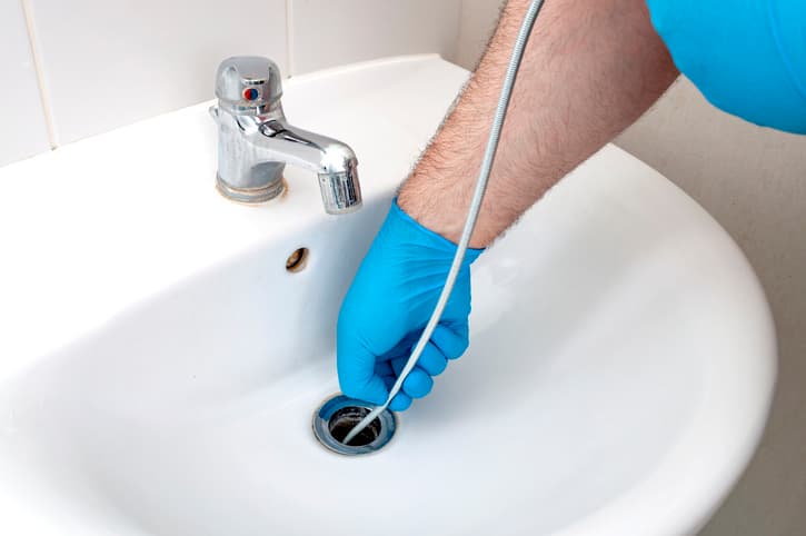 Man using drain snake in sink