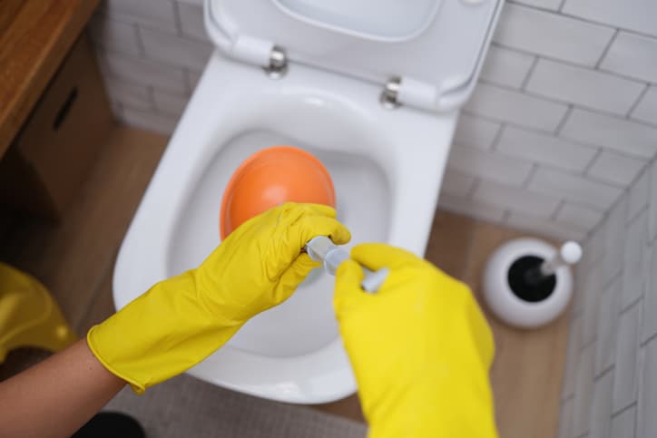 Person using plunger in toilet 