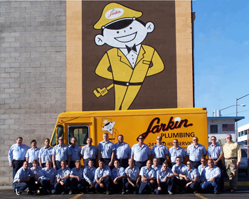 The Larkin Plumbing team standing and kneeling in front of a yellow Larkin Plumbing van